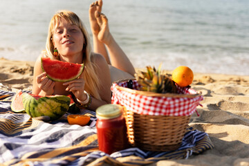Cheerful young woman enjoy at tropical sand beach. Portrait of happy girl with fruit. Young woman having a picnic on the beach..