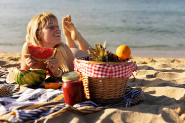 Cheerful young woman enjoy at tropical sand beach. Portrait of happy girl with fruit. Young woman having a picnic on the beach..