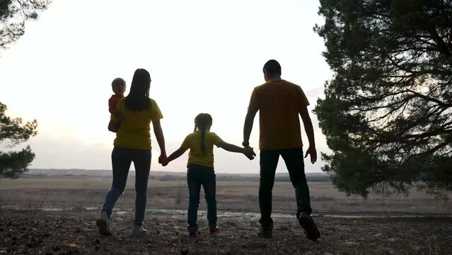 Silhouette of a family walking in the park. happy people together. Family walk in the park at sunset. Silhouette of parents with children. Friendly family concept.