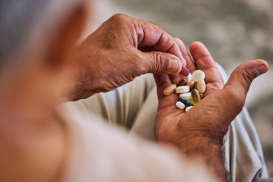 Pills, medicine and healthcare of senior man taking daily capsules for chronic illness, cancer or health. Wellness, medication and sick elderl with medical drugs, vitamins or supplements in his hand