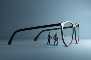 businessman and woman holding hands and looking through abstract huge glasses on gray background....