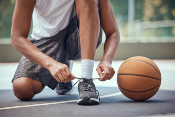 Shoes, basketball and sports with a man basket ball player tying his laces on a court before a game...