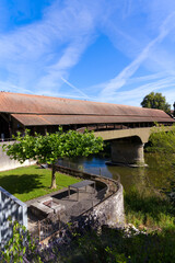 Fototapeta premium Beautiful single lane covered wooden bridge over Thur River connecting villages Andelfingen and Kleinandelfingen on a sunny summer day. Photo taken July 12t, 2022, Andelfingen, Switzerland.