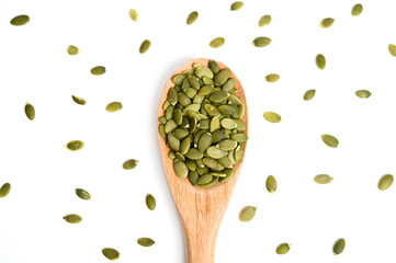 Pumpkin seeds on white background, top view. Pumpkin seeds in wooden spoon. Healthy eating