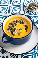 Pumpkin soup with seeds on the tile background in folk style