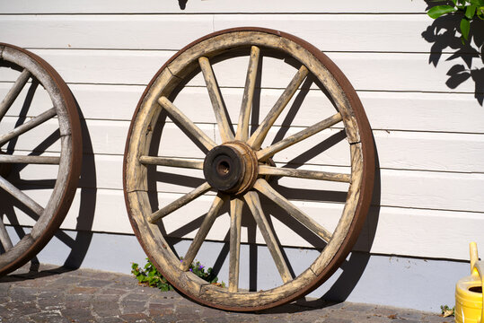 Wooden wheels of carriage leaned against wall of house on a sunny summer day at rural village Andelfingen, Canton Zürich. Photo taken July 12th, 2022, Andelfingen, Switzerland.