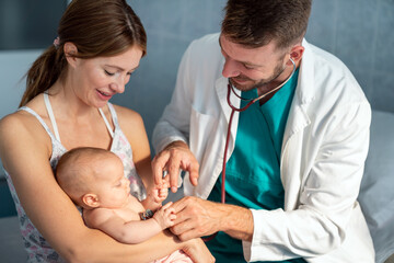 Happy pediatrician doctor with baby checking possible heart defect