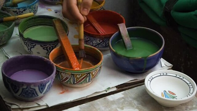 4K Footage of ceramic manufacture man making handcrafted potteryn. Painting traditional Moroccan pottery. Ceramics is traditional industry in Fez