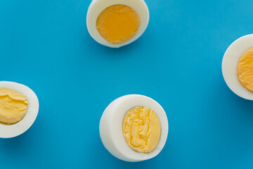 Top view of cut boiled eggs on blue surface.