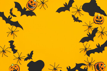 Happy Halloween! Halloween flat lay. Bats, spiders, ghost and pumpkin decoration on yellow. Frame