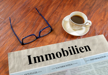 Immobilien Zeitung mit Brille und Kaffee auf einem Schreibtisch