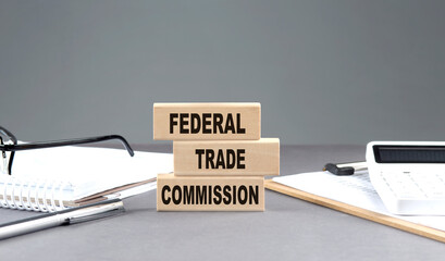 FTC -FEDERAL TRADE COMMISSION text on wooden block with notebook,chart and calculator, grey background - obrazy, fototapety, plakaty