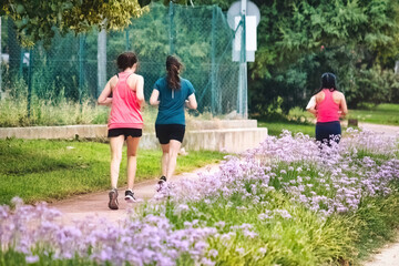 Female runners jogging in a public park area in the summer