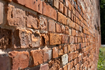 Old weathered red brick wall of an old factory. The surface is partially cracked. 