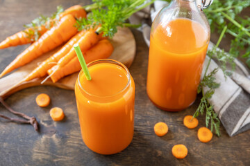Fresh natural juice, healthy food concept. Glass jar of fresh carrot juice with fresh carrots on a rustic table.