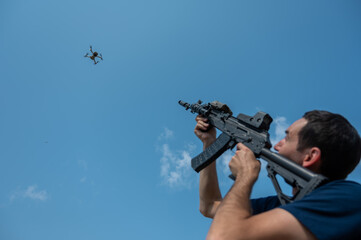 Caucasian man shoots a flying drone with a rifle.