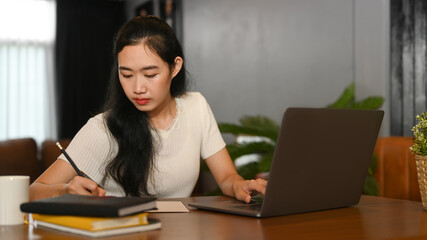 Young asian lady study online on laptop and writing important information on notebook. Education, e-learning, distance training