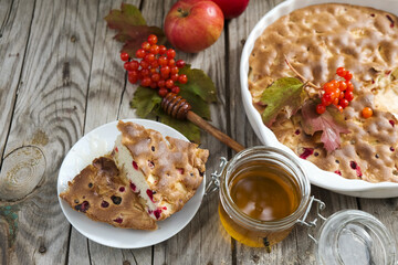 apple pie with cranberries, next to a sprig of viburnum. autumn atmosphere. wooden background.