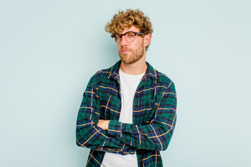 Young caucasian man isolated on blue background suspicious, uncertain, examining you.