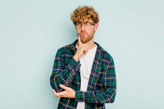 Young caucasian man isolated on blue background contemplating, planning a strategy, thinking about the way of a business.