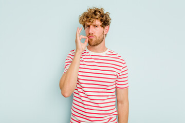 Young caucasian man isolated on blue background with fingers on lips keeping a secret.