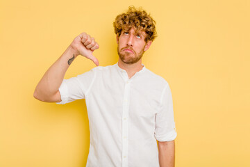 Young caucasian man isolated on yellow background showing a dislike gesture, thumbs down. Disagreement concept.