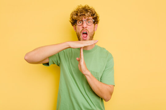 Young caucasian man isolated on yellow background showing a timeout gesture.