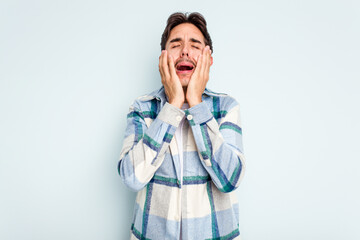 Young hispanic man isolated on blue background crying, unhappy with something, agony and confusion concept.