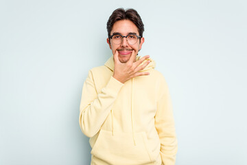 Young hispanic man isolated on blue background doubting between two options.