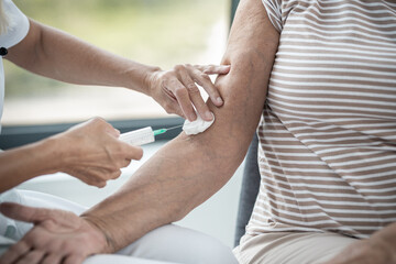 Female blonde senior doctor having a positive talk with senior woman patient and holding hands
Giving vaccine to senior patient