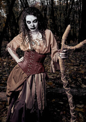 Halloween (Samhain) theme: awful gloomy voodoo witch with stick. Portrait of evil hex in dark...