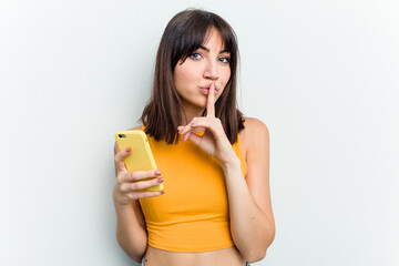 Young caucasian woman using mobile phone isolated on white background keeping a secret or asking for silence.