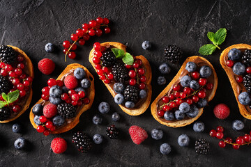 Bread toast with chocolate paste and berries on black background