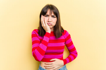 Obraz premium Young caucasian woman isolated on yellow background blows cheeks, has tired expression. Facial expression concept.