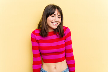 Young caucasian woman isolated on yellow background laughs and closes eyes, feels relaxed and happy.