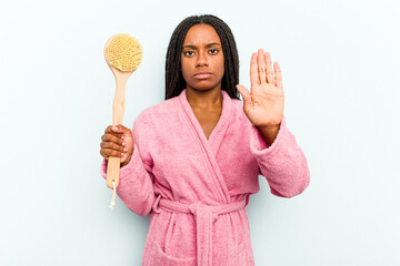 Young African American woman holding a bathtub brush isolated on blue background standing with outstretched hand showing stop sign, preventing you.