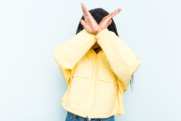 Young African American woman with braids hair isolated on blue background keeping two arms crossed, denial concept.