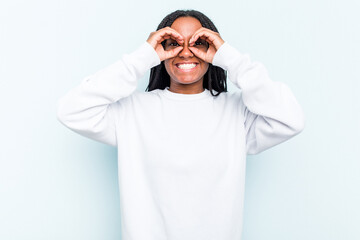 Young African American woman with braids hair isolated on blue background showing okay sign over eyes