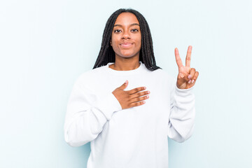 Young African American woman with braids hair isolated on blue background taking an oath, putting hand on chest.