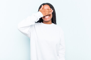 Fototapeta premium Young African American woman with braids hair isolated on blue background covers eyes with hands, smiles broadly waiting for a surprise.