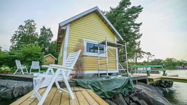 Time lapse of painters, painting newly constructed lake side cottage. Static.