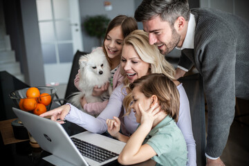 Family having their time in living room, playing with dog while having a video call 