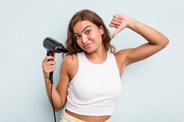 Young caucasian woman holding a hairdryer isolated on blue background feels proud and self confident, example to follow.