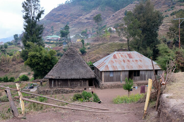 Fototapeta na wymiar A traditional thatched roof Timorese house and a simple tin roof house in the mountains and rural countryside in the districts of Timor Leste, Southeast Asia