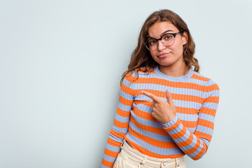 Obraz premium Young caucasian woman isolated on blue background smiling and pointing aside, showing something at blank space.