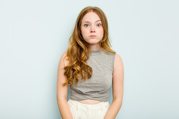 Young caucasian woman isolated on blue background shrugs shoulders and open eyes confused.