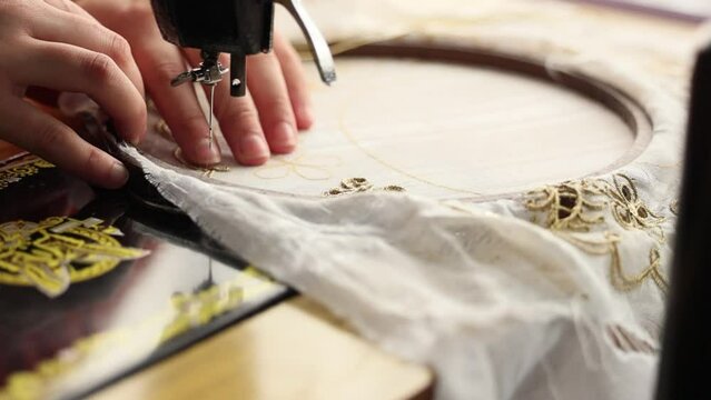 Tailor sewing on a round needlepoint canvas with golden lining