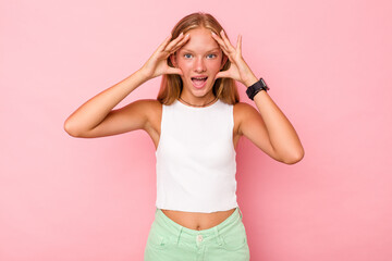 Caucasian teen girl isolated on pink background receiving a pleasant surprise, excited and raising...