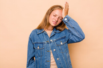 Caucasian teen girl isolated on beige background forgetting something, slapping forehead with palm and closing eyes.