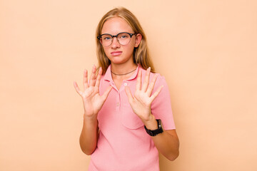 Caucasian teen girl isolated on beige background rejecting someone showing a gesture of disgust.